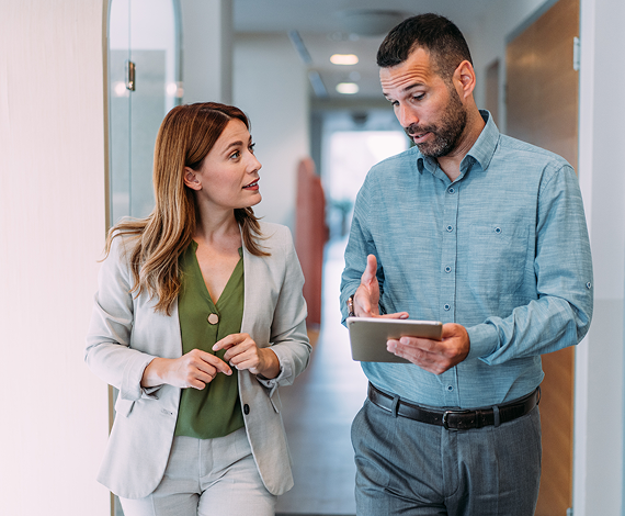 Business colleagues discussing project details while walking through an office