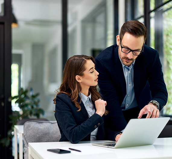 Colleagues reviewing business information together on a laptop