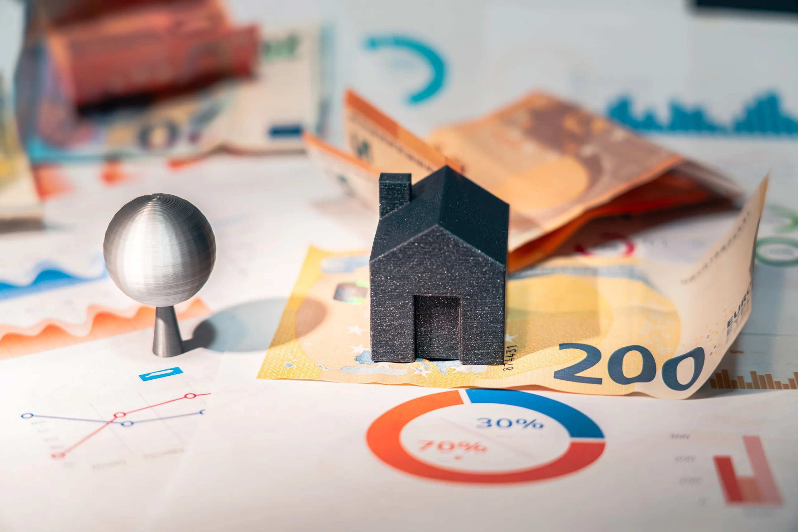 House model with euro banknotes and financial charts representing property investment